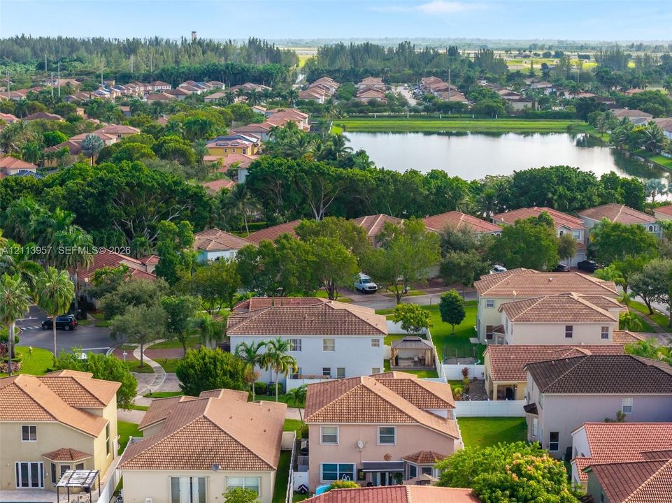 Aerial perspective of a residential community featuring tile roofing, mature landscaping, and a central water feature