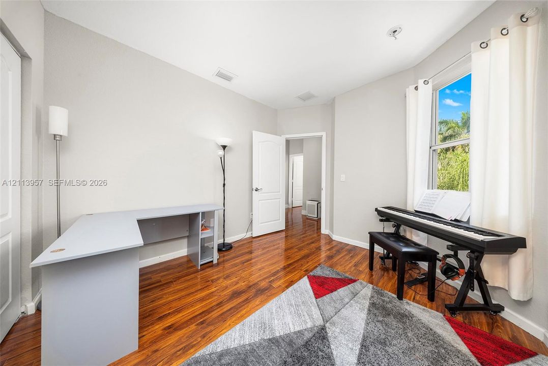Room featuring polished wood-finish flooring, a neutral color palette, and natural light from an oversized window