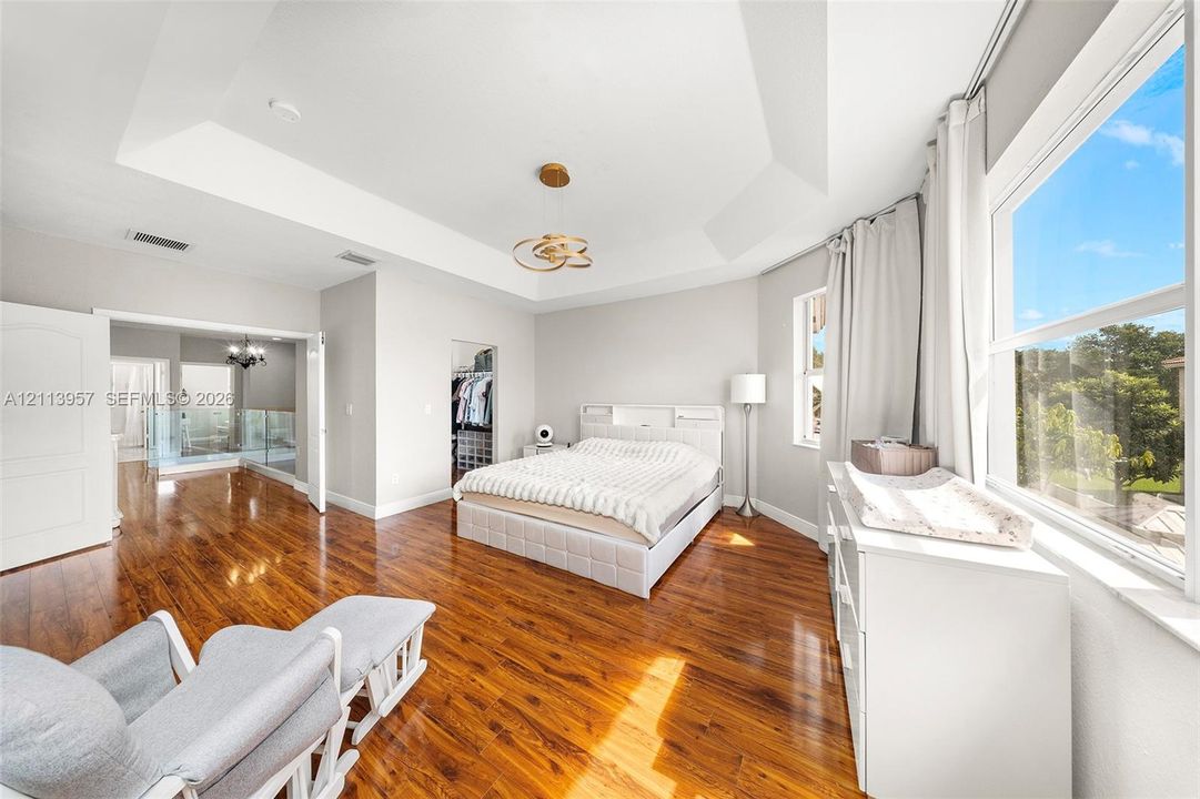 Tray ceiling featuring a contemporary light fixture, wood-finish flooring, and expansive windows