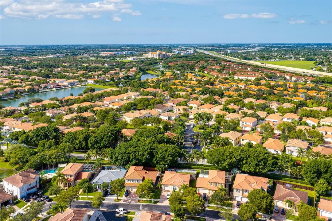 Aerial perspective featuring dense mature tree canopies, tile roofing, and prominent water features