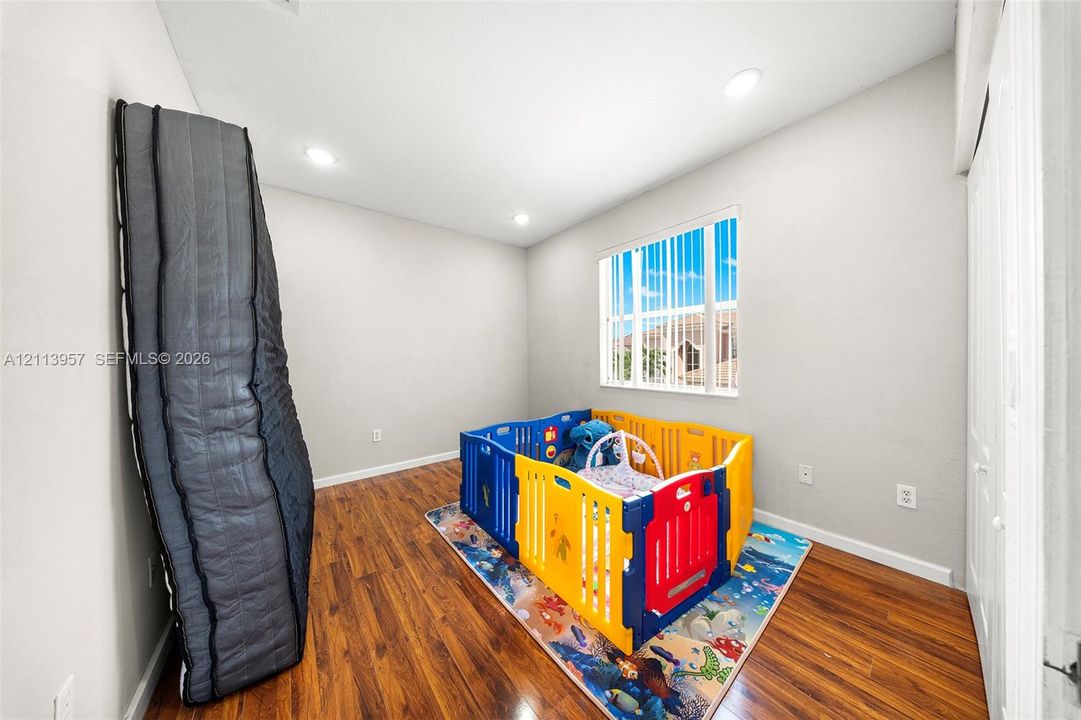 Interior room featuring wood-finish flooring, recessed lighting, and a window with vertical blinds