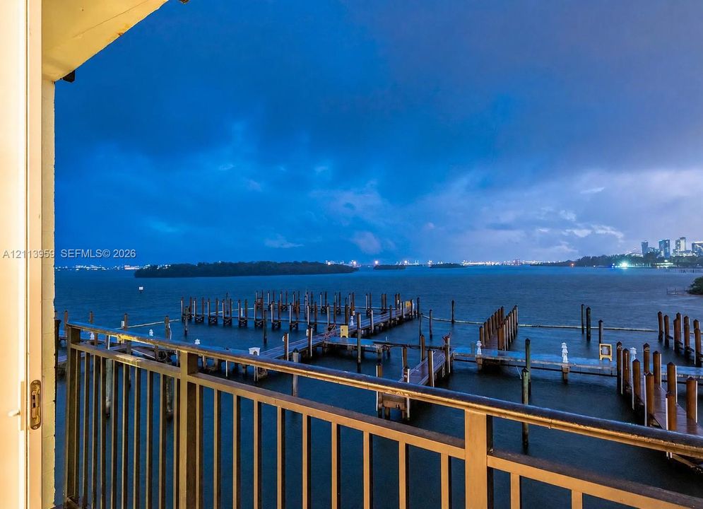 Balcony with metal railing overlooking a private dock system and expansive water frontage