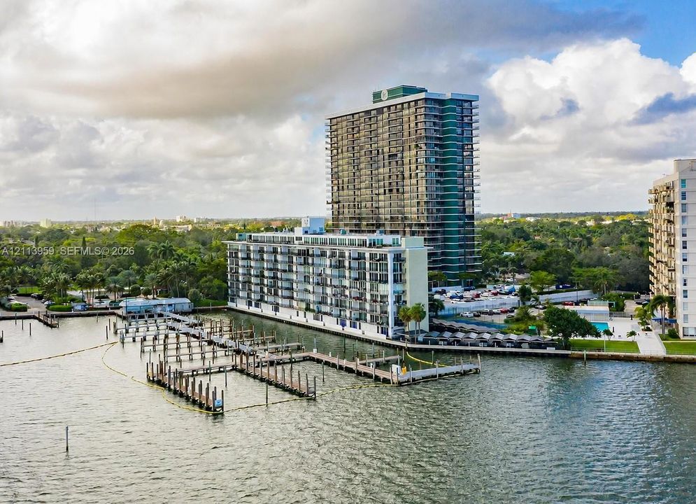 Waterfront high-rise building featuring private boat slips, multi-level balconies, ground-level swimming pool, and structured parking