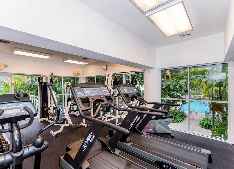 Fitness center featuring floor-to-ceiling windows, high ceilings with recessed lighting, and a rubberized flooring surface