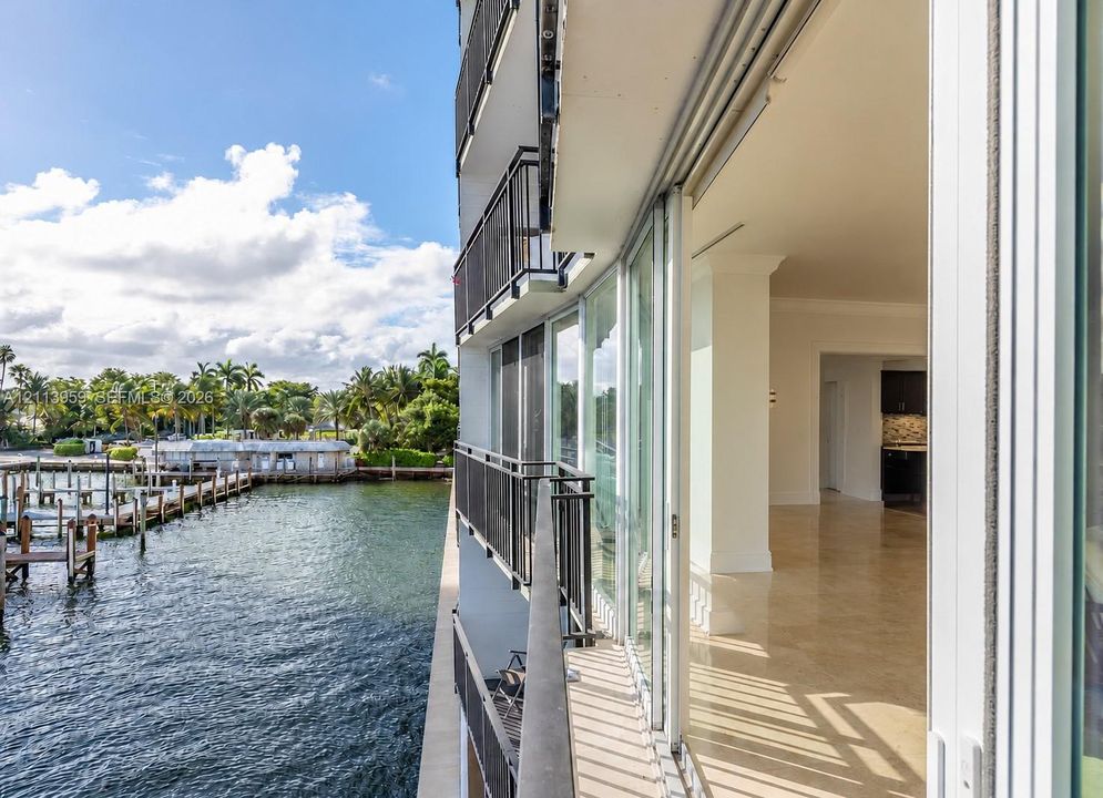 Covered balcony featuring metal railings and floor-to-ceiling glass sliding doors, stone flooring, and expansive water exposure