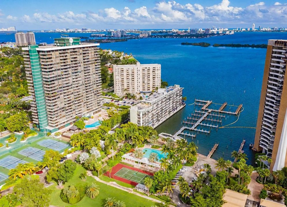 Waterfront condominium complex featuring a deep-water marina, multiple swimming pools, tennis courts, and landscaped grounds