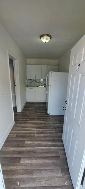 Kitchen area featuring white cabinetry, wood-finish flooring, and a stone-patterned backsplash