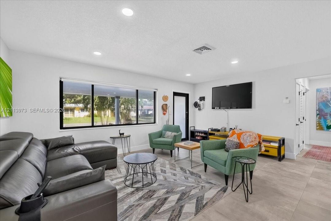 Living area featuring large format tile flooring, recessed lighting, and a picture window
