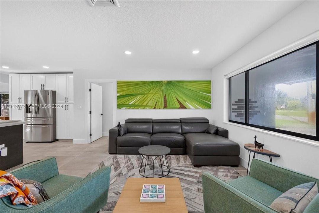 Open-concept interior featuring large-format tile flooring, recessed lighting, and expansive horizontal picture windows