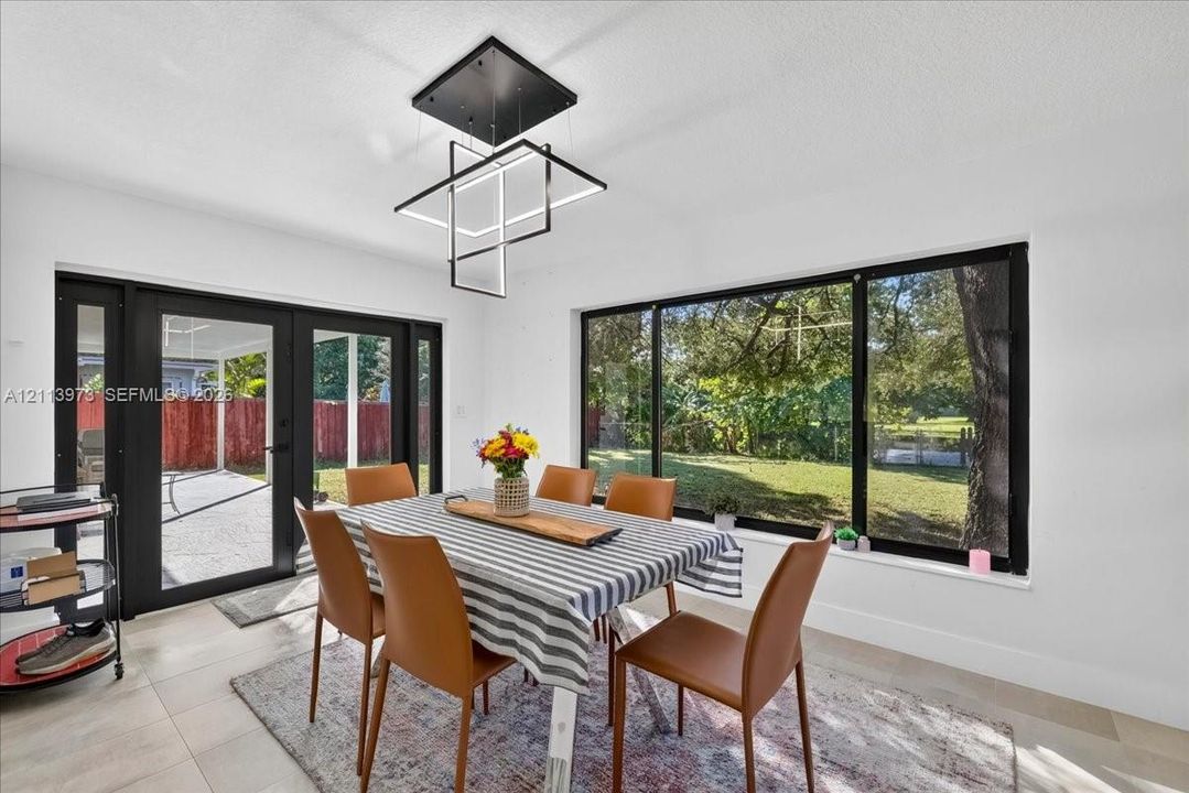 Modern matte black geometric chandelier, large-format tile flooring, and expansive windows with black frames