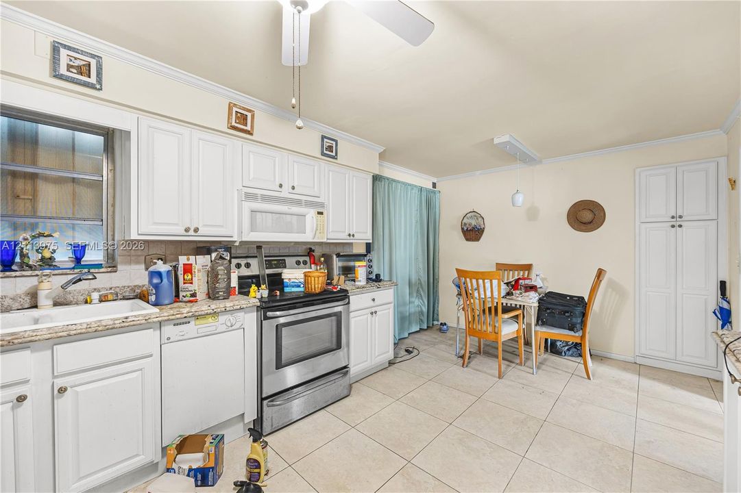Kitchen featuring white cabinetry, stone-finish countertops, stainless steel appliances, ceramic tile flooring, and a built-in pantry
