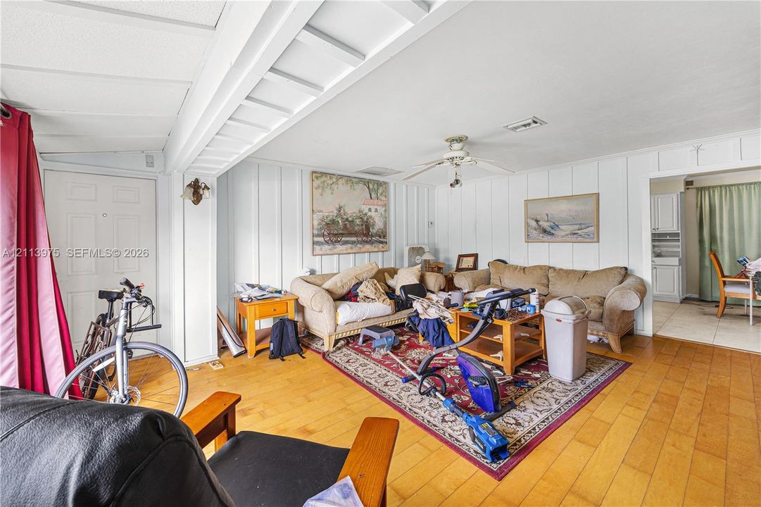 Interior featuring wood-finish flooring, vertical plank wall paneling, and a ceiling-mounted fan