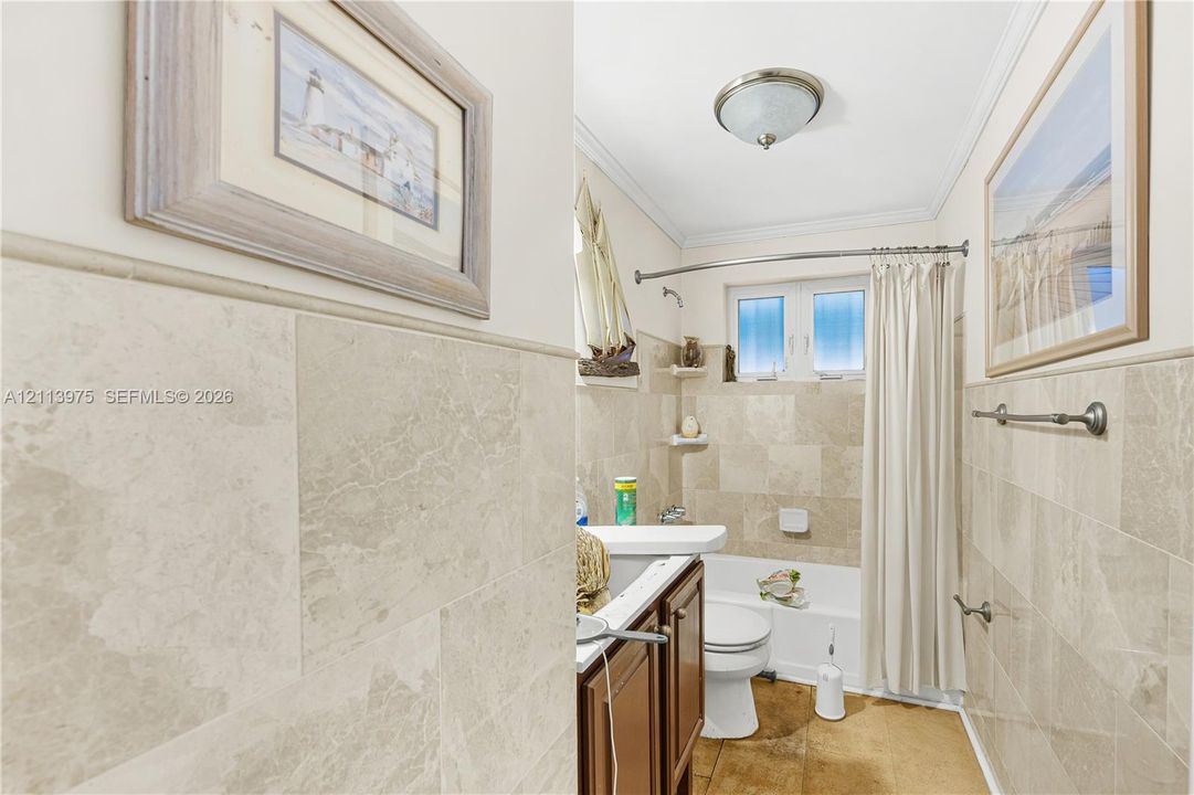 Full-height stone wall tiling with matching crown molding, wood-finish cabinetry, and built-in recessed wall shelving