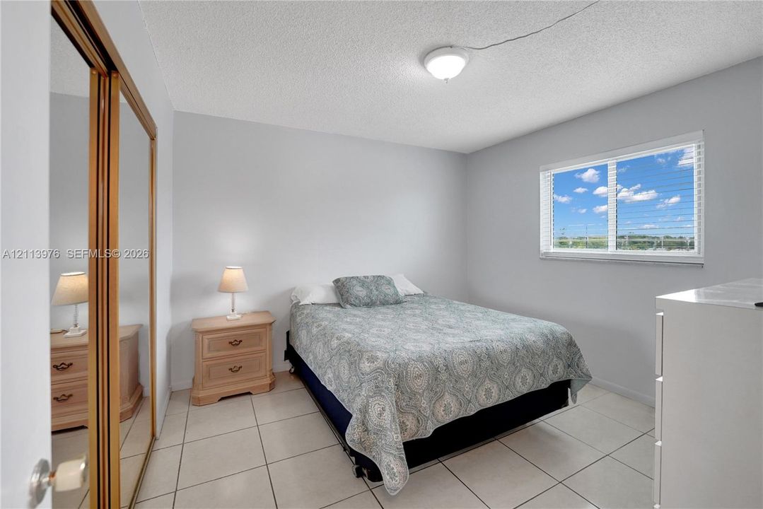 Neutral wall finishes, large-format tile flooring, sliding mirror-panel closet doors, and a horizontal sliding window