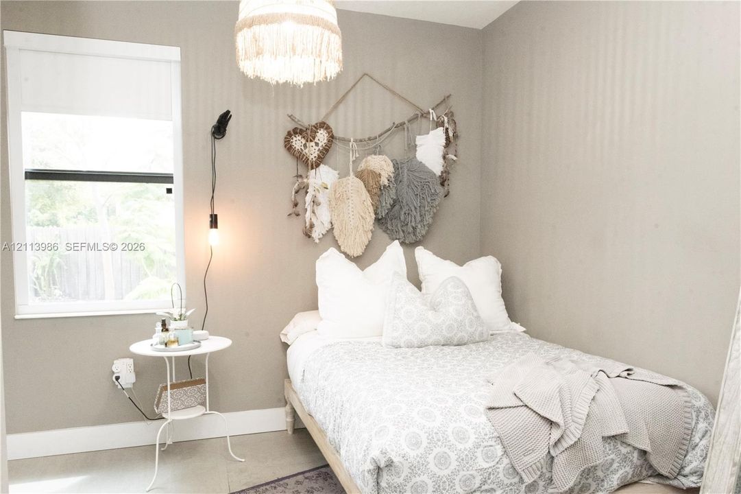 Ground floor bedroom, Neutral-toned interior space featuring a single-hung window, a decorative pendant light fixture, and a wall-mounted light fixture with a corded finish