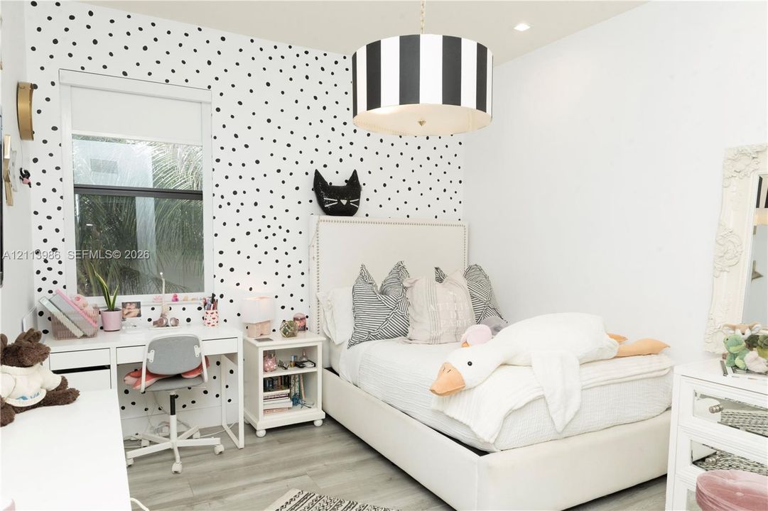 Polka-dot patterned accent wall, grey wood-finish flooring, and recessed ceiling lighting