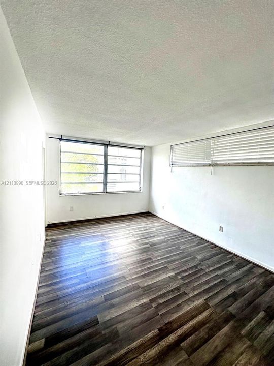 Interior space featuring wood-finish flooring, white walls, and multi-pane windows with horizontal blinds