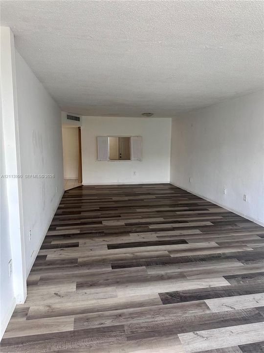 Interior space featuring multi-tonal wood-finish flooring, neutral walls, and a cutout wall pass-through