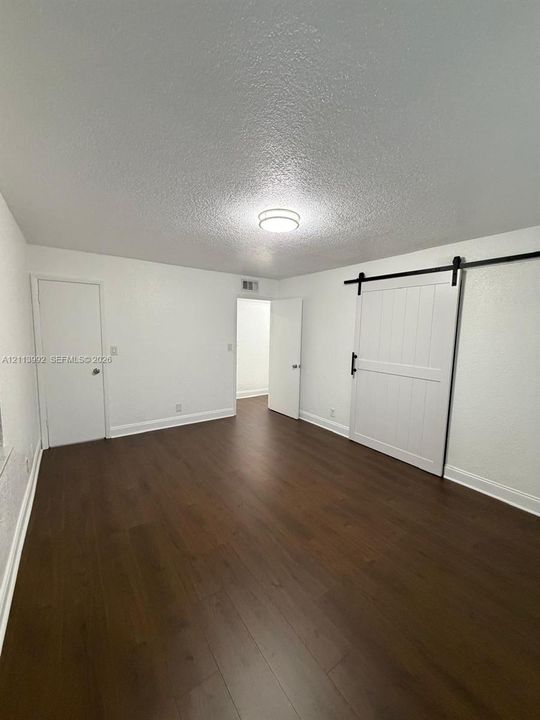 Interior space featuring wood-finish flooring, white walls, flush-mount ceiling lighting, and a white sliding barn-style door with matte black hardware