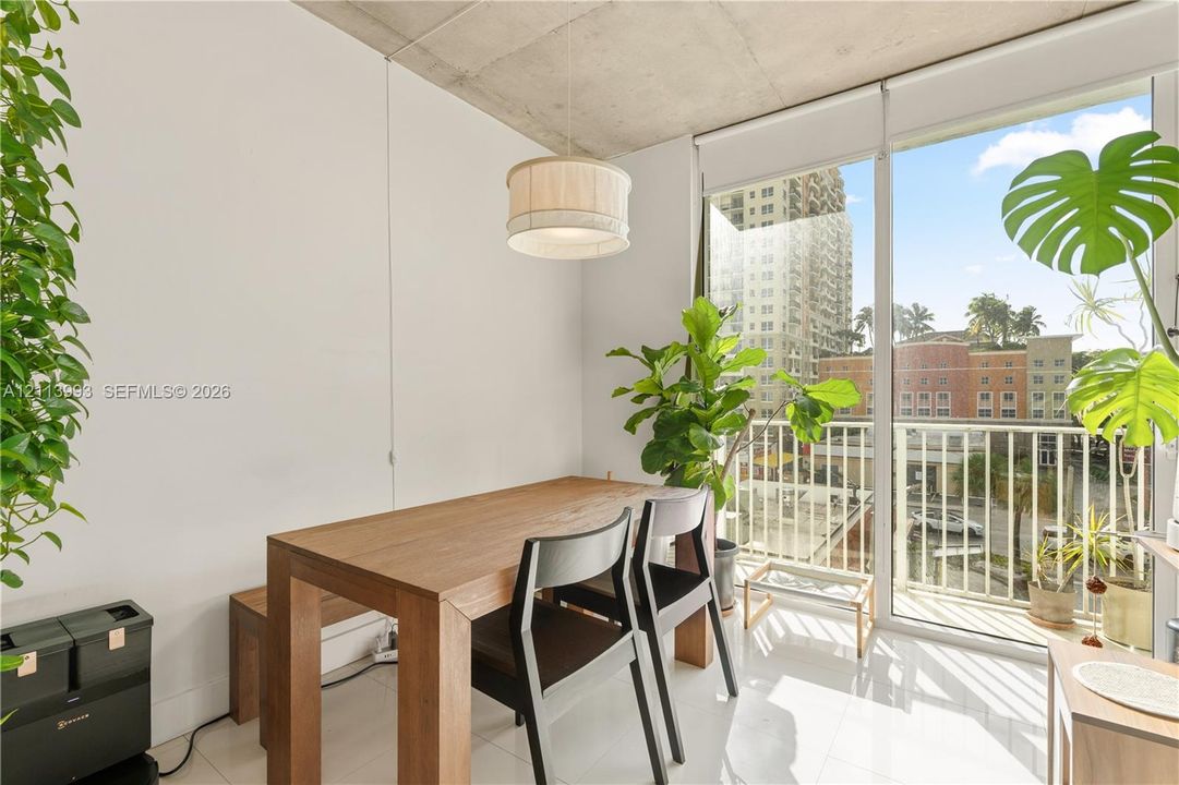 Exposed concrete ceiling, floor-to-ceiling glass door, polished tile flooring, and a drum-style pendant light fixture