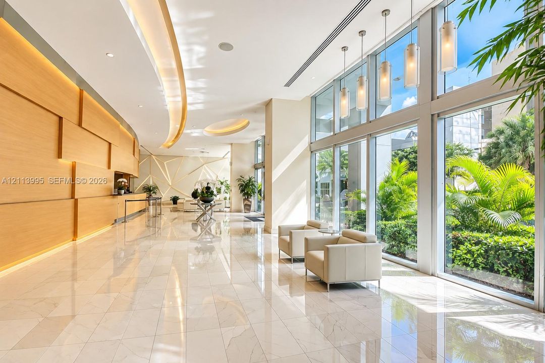 Floor-to-ceiling glass windows, polished tile flooring, wood-paneled accent wall with recessed lighting, custom geometric wall detailing, and a series of hanging pendant lights