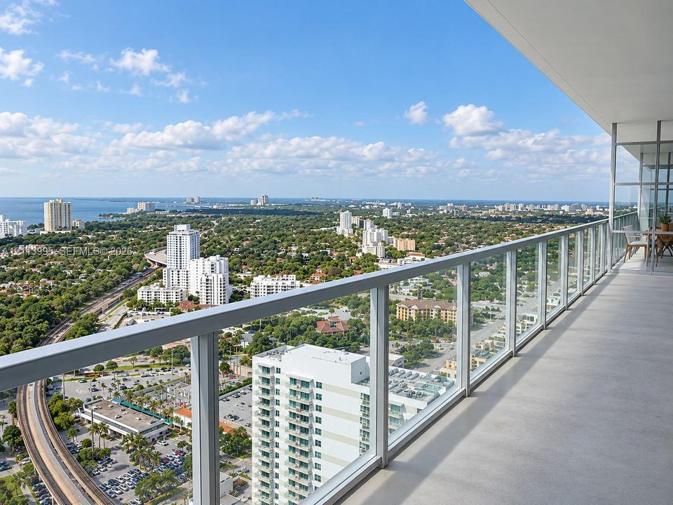 Expansive covered balcony featuring a concrete floor and a full-height glass railing