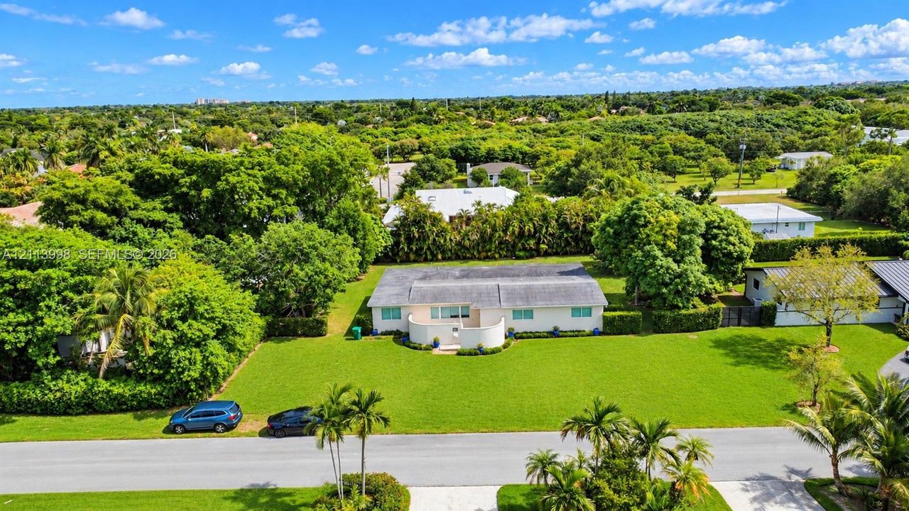 Single-story residence featuring a gated entry courtyard, expansive front lawn, and mature landscaping