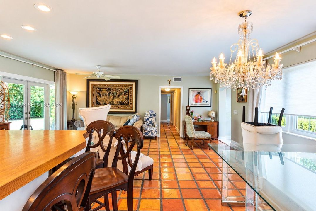 Terracotta tile flooring, decorative crystal chandelier, recessed lighting, and glass paneled French doors