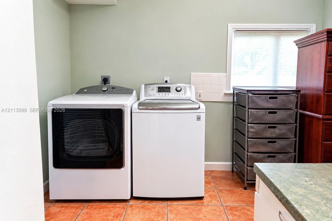 Dedicated laundry area featuring ceramic tile flooring, neutral wall tones, and a window with blinds