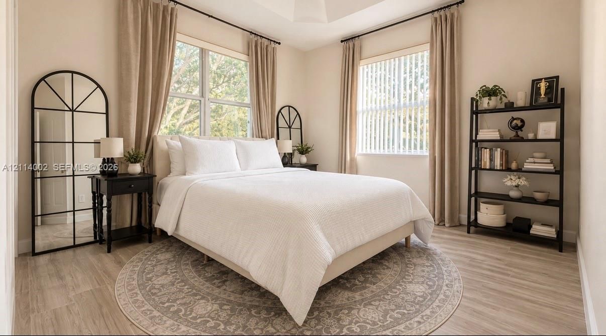 Tray ceiling, wood-finish flooring, and multiple large windows with neutral-toned treatments