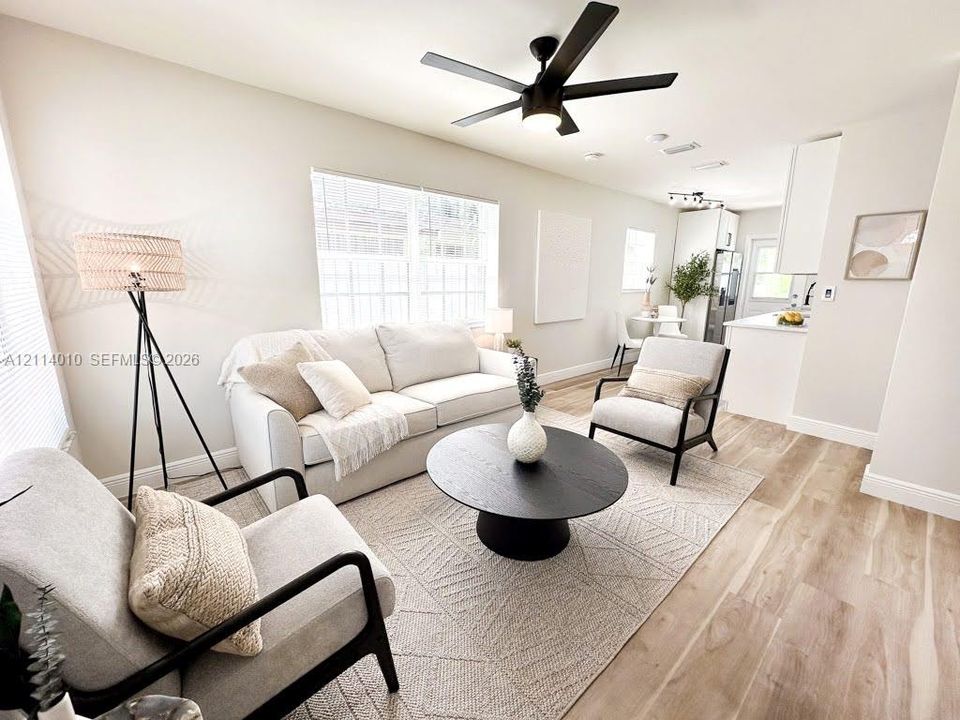 Open-concept interior featuring light wood-finish flooring, recessed lighting, matte black ceiling fan with integrated lighting, and white cabinetry