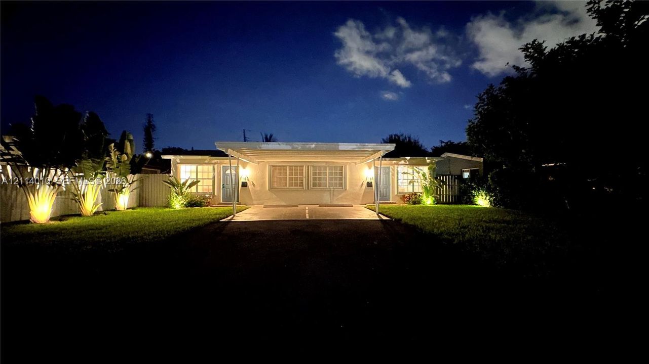 Single-story residence featuring a paved driveway, attached carport, grid-pattern windows, and landscaped front lawn