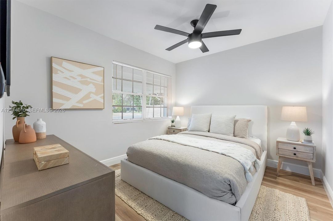 Multi-pane window, wood-finish flooring, and matte black five-blade ceiling fan with integrated lighting