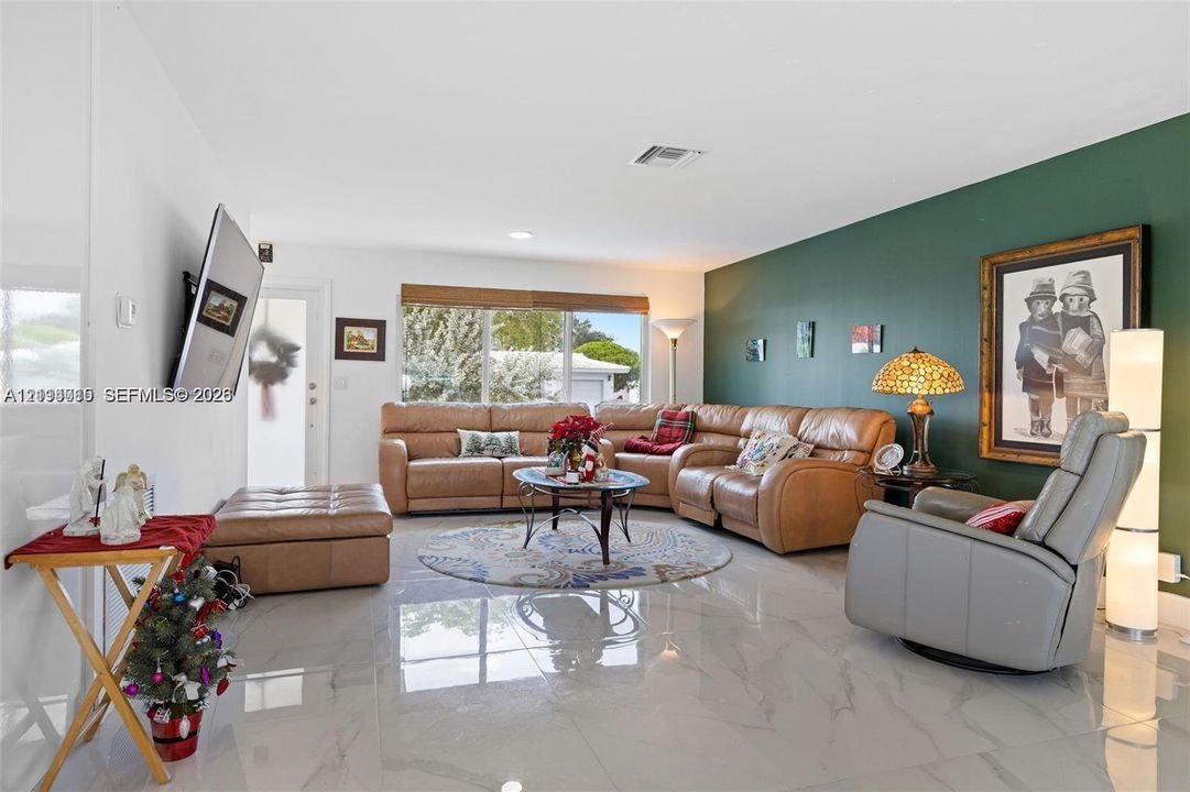 Spacious interior featuring large-format polished tile flooring, recessed ceiling lighting, and a prominent accent wall