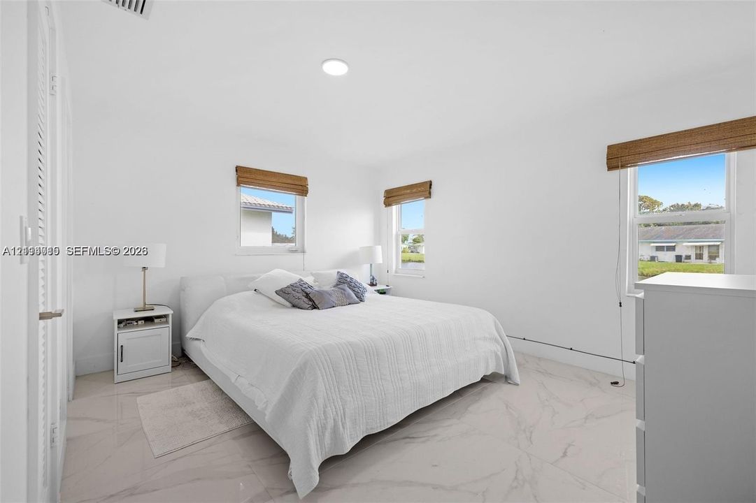Bright room featuring polished stone-finish flooring, recessed lighting, and multiple windows with woven wood shades