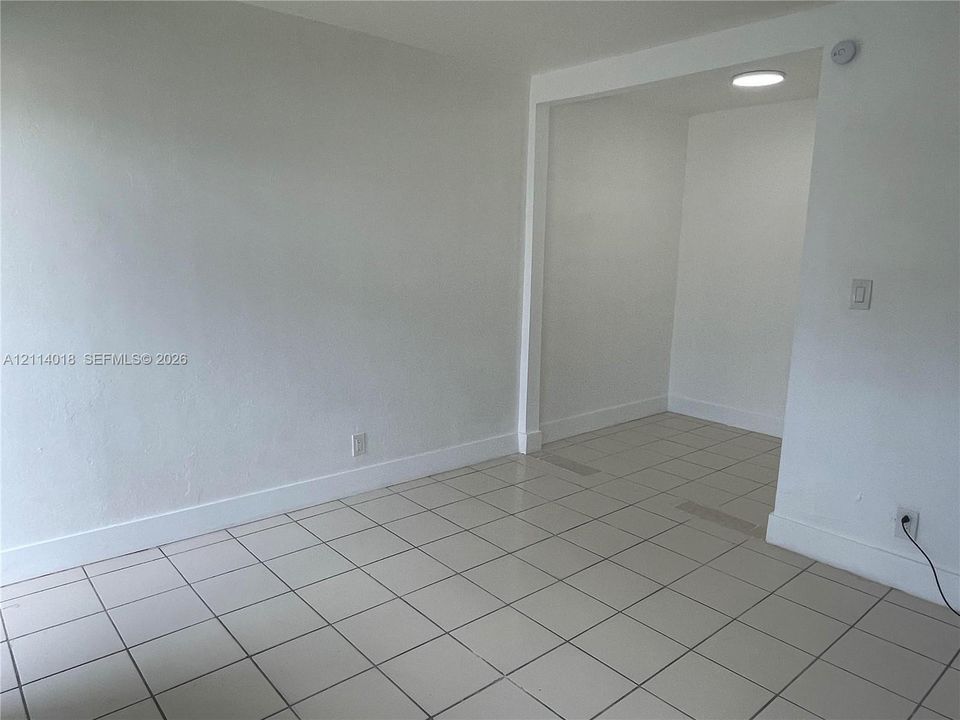 Neutral-toned interior space featuring ceramic tile flooring, smooth white walls, and recessed ceiling lighting