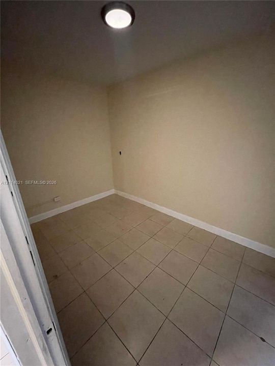 Interior room featuring light-colored tile flooring, smooth walls, and a ceiling-mounted light fixture