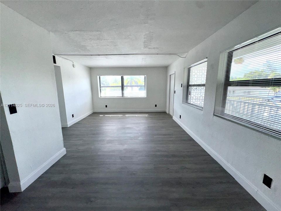 Neutral interior space featuring wood-finish flooring, multi-pane windows, and minimalist wall finishes