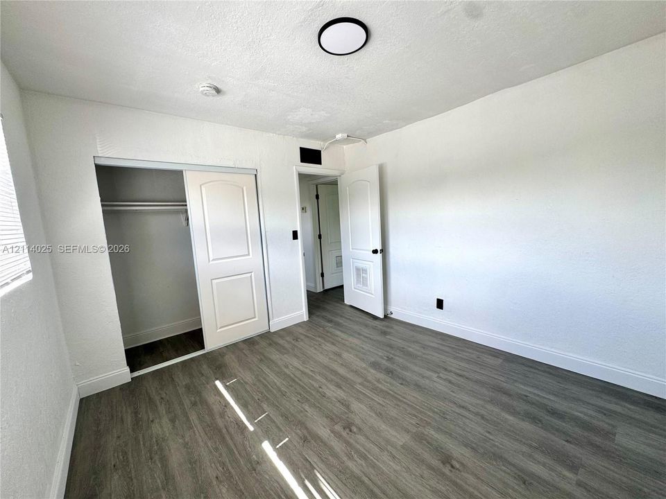 Room featuring wood-finish flooring, two-panel interior doors, a sliding closet door, and a flush-mount circular ceiling light