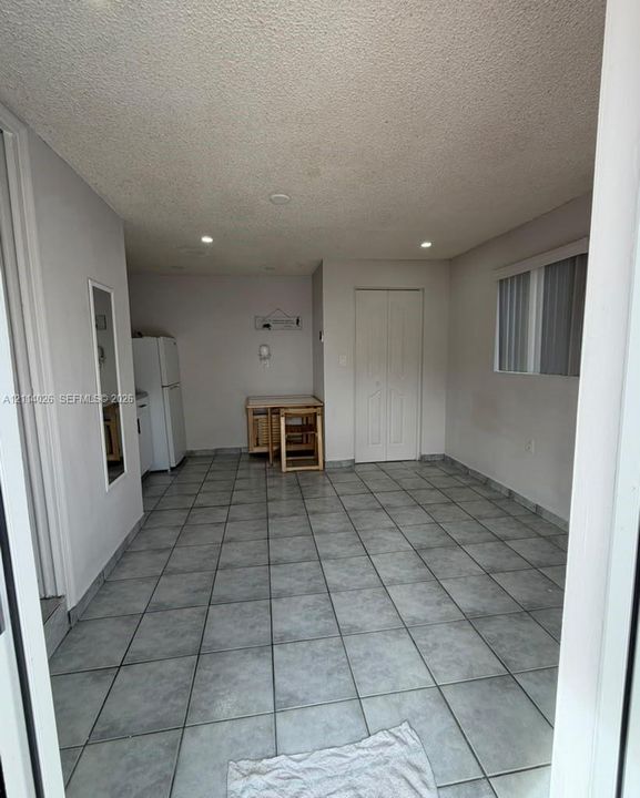 Large-format tile flooring, recessed ceiling lighting, and double-door closet with paneled detailing