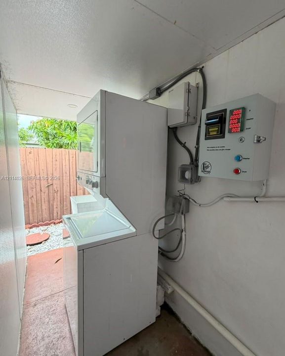 Stacked white laundry unit featuring a top-load washer and a control panel for integrated utility management