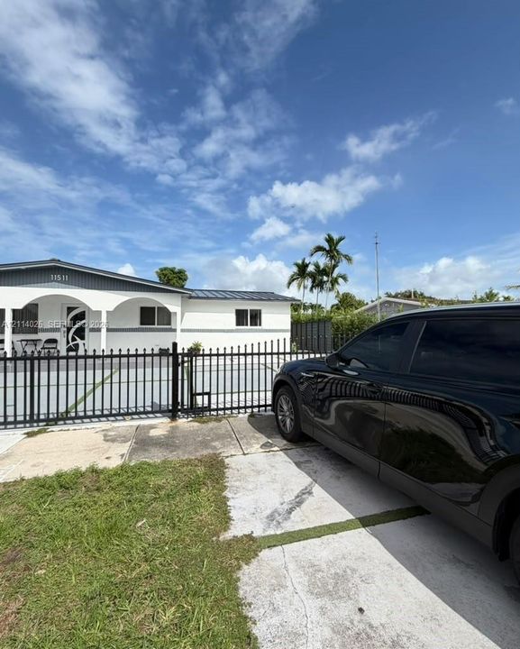 Single-story exterior featuring a metal roof, arched covered entryway, and a secured perimeter with a decorative metal fence