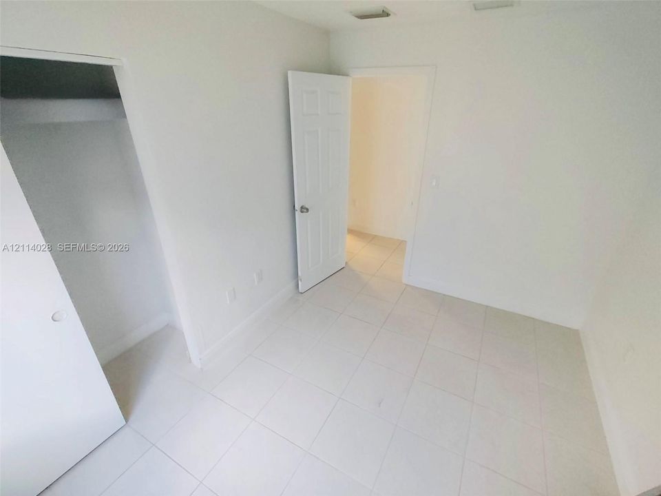 Interior room featuring neutral ceramic tile flooring, six-panel doors, and a built-in closet with a shelf