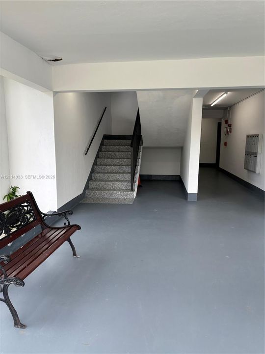 Common area featuring a stone-finish staircase, black metal handrails, a multi-unit wall-mounted mailbox system, and smooth flooring