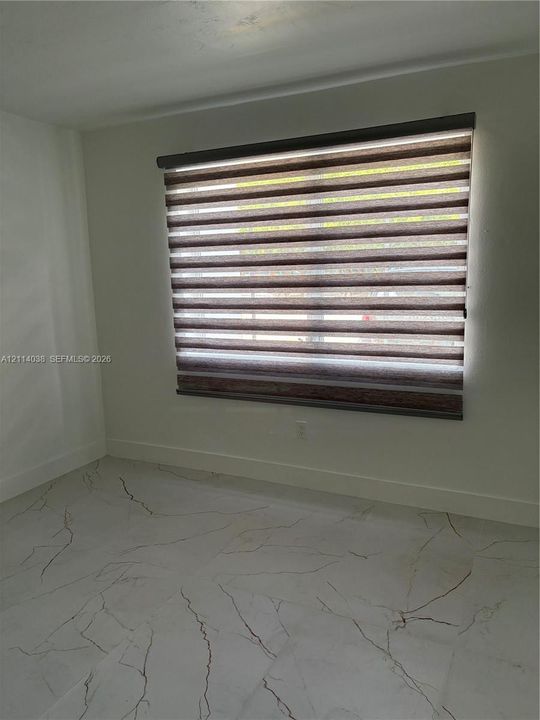 Large-format tile flooring featuring a veined pattern, paired with dual-layered fabric window shades