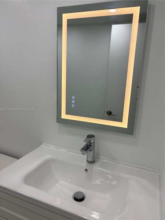 Rectangular vanity with an integrated white sink basin, polished chrome single-handle faucet, and wall-mounted rectangular mirror with an integrated LED border
