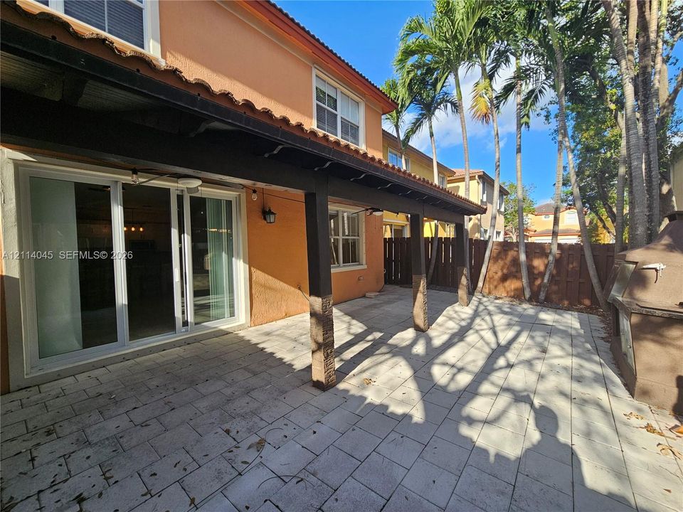 Covered patio featuring paver flooring, support columns with stone-finish bases, and sliding glass doors
