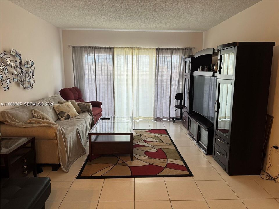 Living area featuring neutral-tone tile flooring and floor-to-ceiling sliding glass doors