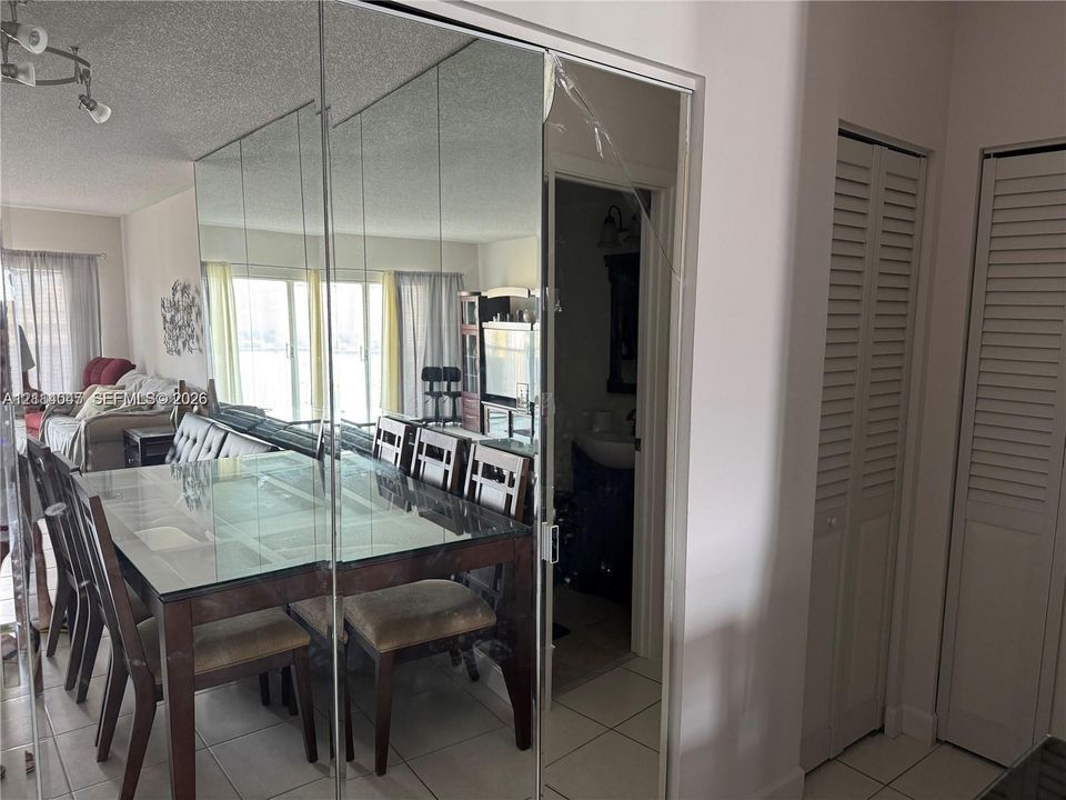 Full-height mirrored wall panel, tiled flooring, and dual bi-fold louvered closet doors