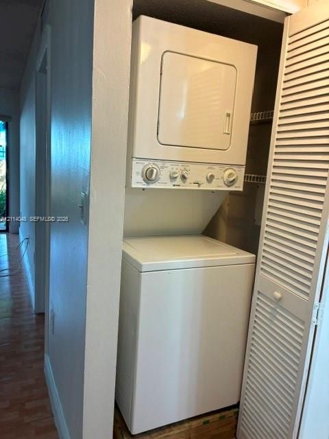 Stacked laundry appliance set featuring a top-loading washer and front-loading dryer, housed within a closet with white louvered doors and integrated wire shelving